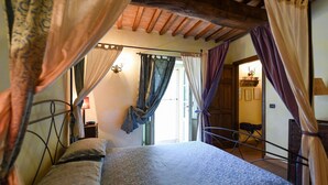 A bedroom with a bed, curtains, a nightstand, and a lamp. - Belvilla by OYO Macetona - Suite (San Casciano dei Bagni)