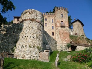 A historic stone castle with a large round tower and a rectangular building with battlements. - Belvilla by OYO Casa de Poi (Salsomaggiore Terme)