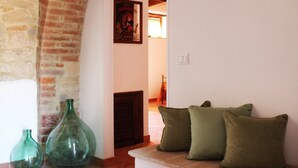 Ein gemütliches Wohnzimmer mit einer Ziegelbogenarchitektur, einem grünen Sofa mit Kissen und zwei grünen Vasen auf dem Boden.