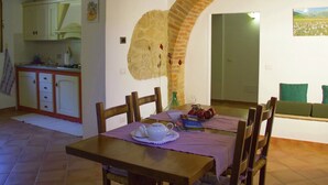 Ein Essbereich mit Ziegelbogen, Holzkästen, einem Tisch mit Teekanne und Blick auf Küche und Wohnzimmer.