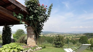 Un jardín con un pilar de piedra, una silla blanca y vistas al campo.