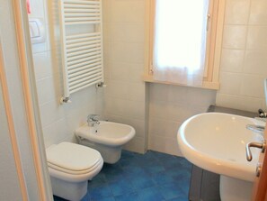Ein Badezimmer mit zwei Toiletten, einem Waschbecken und einem Fenster mit Vorhang.
