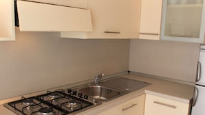 Een keuken met een gasfornuis, een spoelbak en witte kasten.