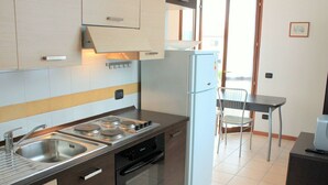 A modern kitchen with stainless steel appliances, a dishwasher, and a dining area with a chair and table. - Belvilla by OYO Casa Gialla A Due (Lazise)