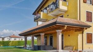 A two-story house with a covered patio, a balcony, and a swimming pool in the background. - Belvilla by OYO Casa Gialla A Due (Lazise)