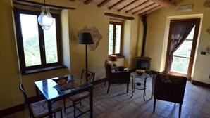 Une pièce chaleureuse avec un plafond en bois, une table avec des chaises, une lampe et une cheminée.