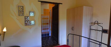 A bedroom with a bed, a wardrobe, a radiator, and a wall-mounted light fixture.