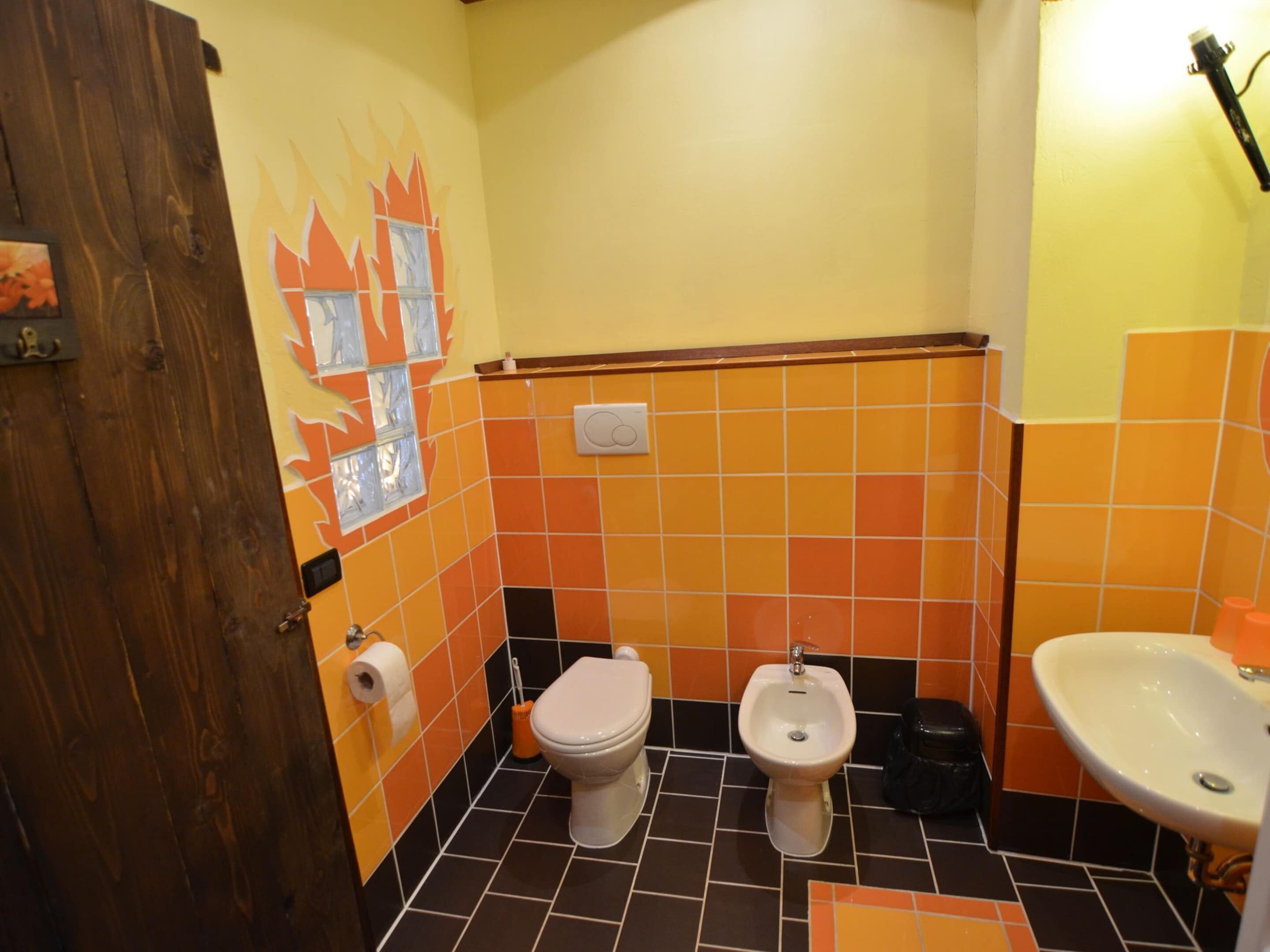 A bathroom with two toilets, a bidet, and a sink.