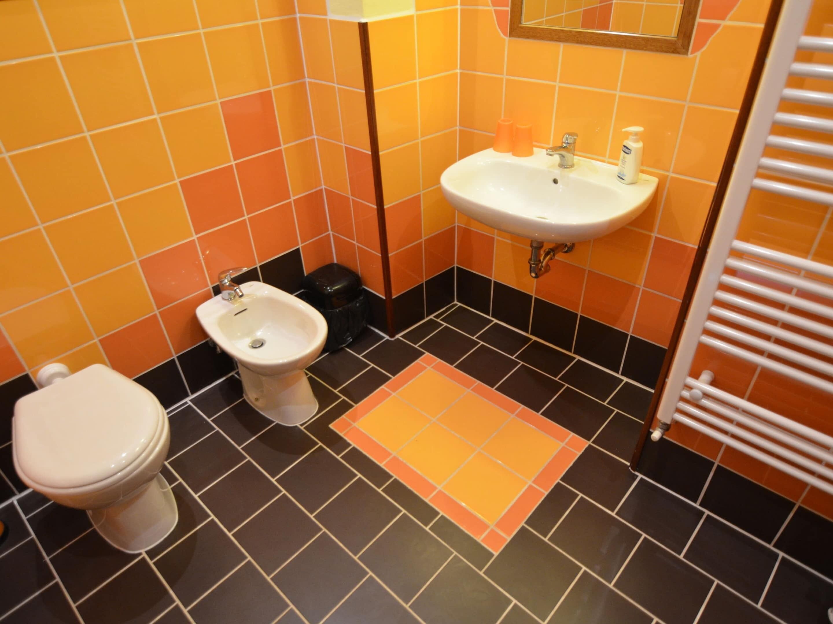 A bathroom with a toilet, bidet, sink, and a towel rack.