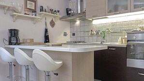 Una cocina moderna con una isla central, taburetes de bar y electrodomésticos de acero inoxidable.