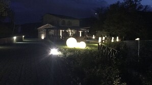 Una casa con un jardín delantero bien iluminado, una cerca y una esfera grande iluminada en el centro.