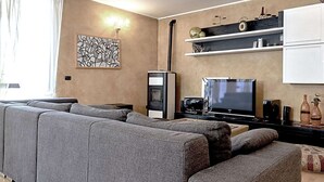 Una sala de estar moderna con un sofá seccional gris, un televisor de pantalla plana y una chimenea.