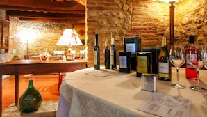 Interior de un restaurante con pared de piedra, vigas de madera, una mesa con botellas de vino, copas y una carta.