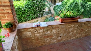 Un muro de piedra con un repisa de ladrillo, plantas en macetas y una revista sobre la repisa.