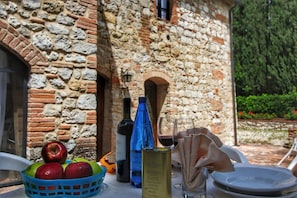 Une table avec un panier de pommes, une bouteille dâhuile dâolive, un verre de vin rouge et une boĂźte de thon.