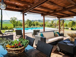Eine Terrasse im Freien mit Korbmöbeln, einem Pool und Blick auf die Landschaft.
