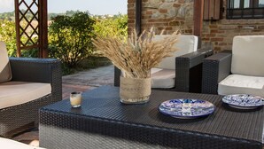A patio with wicker furniture, a glass vase with dried plants, and decorative plates. - Magnificent old Country House With Garden and Private Pool, With Wifi (Salsomaggiore Terme)