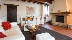 A cozy living room with a fireplace, a dining area with a table and chairs, and a large map on the wall. - Magnificent old Country House With Garden and Private Pool, With Wifi (Salsomaggiore Terme)
