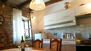 Cucina accogliente con tavolo da pranzo per due persone, frigorifero, fornello e finestra con tende.