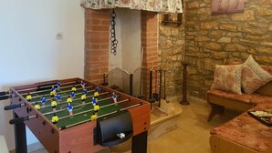 Una stanza accogliente con un tavolo da calcio, un camino e un muro in pietra.