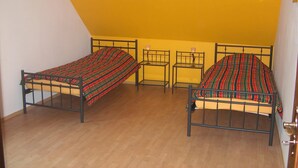 Ein Zimmer mit zwei Betten, jeweils mit gemusterten Bettdecken, einem kleinen Tisch mit einer Lampe und einer Wandleuchte.