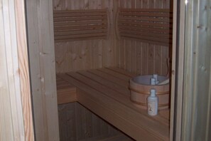 A wooden sauna with benches and a wooden bench with a sink and bottle. - Large Luxury House with Sauna & Hot Tub in Giant Mountains near ski Area (Podgorzyn)