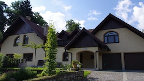 Ein zweistöckiges Haus mit Natursteinfassade, zahlreichen Fenstern und einer Garage.