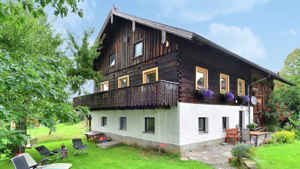 A rustic wooden house with a balcony, a paved patio, and outdoor seating. - Ferienhaus in Bayern mit Waldblick (Viechtach)