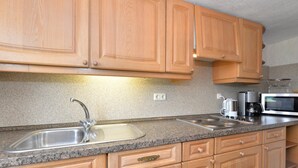 A kitchen with wooden cabinets, a granite countertop, a stainless steel sink, a coffee maker, and a microwave. - Ferienhaus in Bayern mit Waldblick (Viechtach)