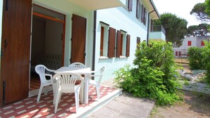 A two-story building with a covered patio area featuring a table and chairs. - Sun Drenched Seaside Holiday Home near Venice (Rosolina)