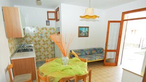 A small, cozy kitchen with a dining table and chairs, a sofa, and a window. - Sun Drenched Seaside Holiday Home near Venice (Rosolina)