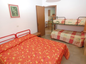 Um quarto em dormitório com duas beliches, uma mesinha e uma cadeira.