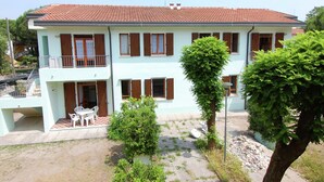A two-story building with a tiled roof, multiple windows with shutters, and a balcony on the upper floor. - Sun Drenched Seaside Holiday Home near Venice (Rosolina)