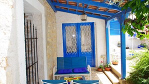 A covered outdoor seating area with blue chairs and a table, a blue door with a window, and a stone wall. - Holiday Villa in Village Rakalj (Marcana)
