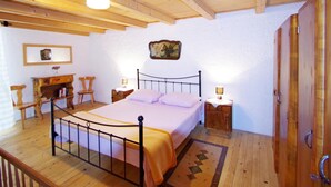 A wooden-floored bedroom with a bed, bedside tables, a chair, and a wooden wardrobe. - Holiday Villa in Village Rakalj (Marcana)