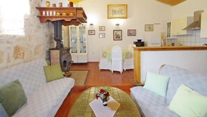 A cozy living room with a fireplace, two sofas, a dining table, and a kitchen area. - Holiday Villa in Village Rakalj (Marcana)