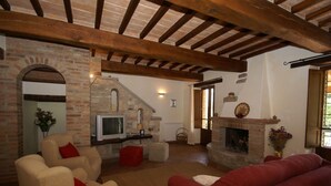 A living room with a fireplace, a television, and a stone wall. - Villa in Umbertide With Pool and Garden (Umbertide)