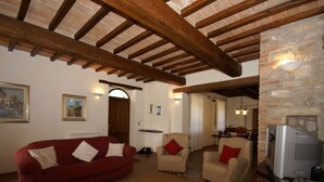 A living room with a red sofa, beige armchairs, and a television. - Villa in Umbertide With Pool and Garden (Umbertide)