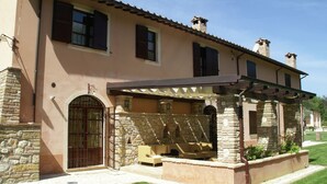 A two-story house with a stone facade, a covered patio with outdoor furniture, and a gated entrance. - Farmhouse in Montoro Near Montoro Castle (Narni)
