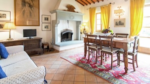 Una sala de estar con chimenea, una mesa de comedor con sillas, un sofá y una televisión.