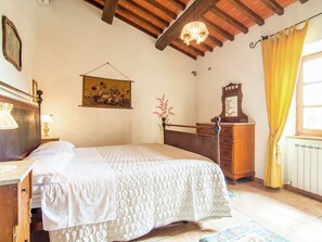 Ein Schlafzimmer mit einem Bett, einer Holzkommode und einem Blumenbild.