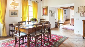 Un comedor con una mesa y sillas de madera, cortinas amarillas y un frutero.