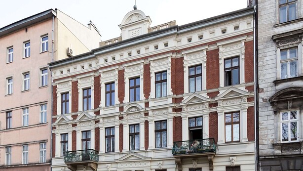 Un edificio histórico con fachada simétrica, ventanas amplias y elementos decorativos.