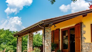 A house with a stone facade, a tiled roof, and a porch with chairs and potted plants. - Cottage in Tuscany With Private Pool (Montecatini Terme)