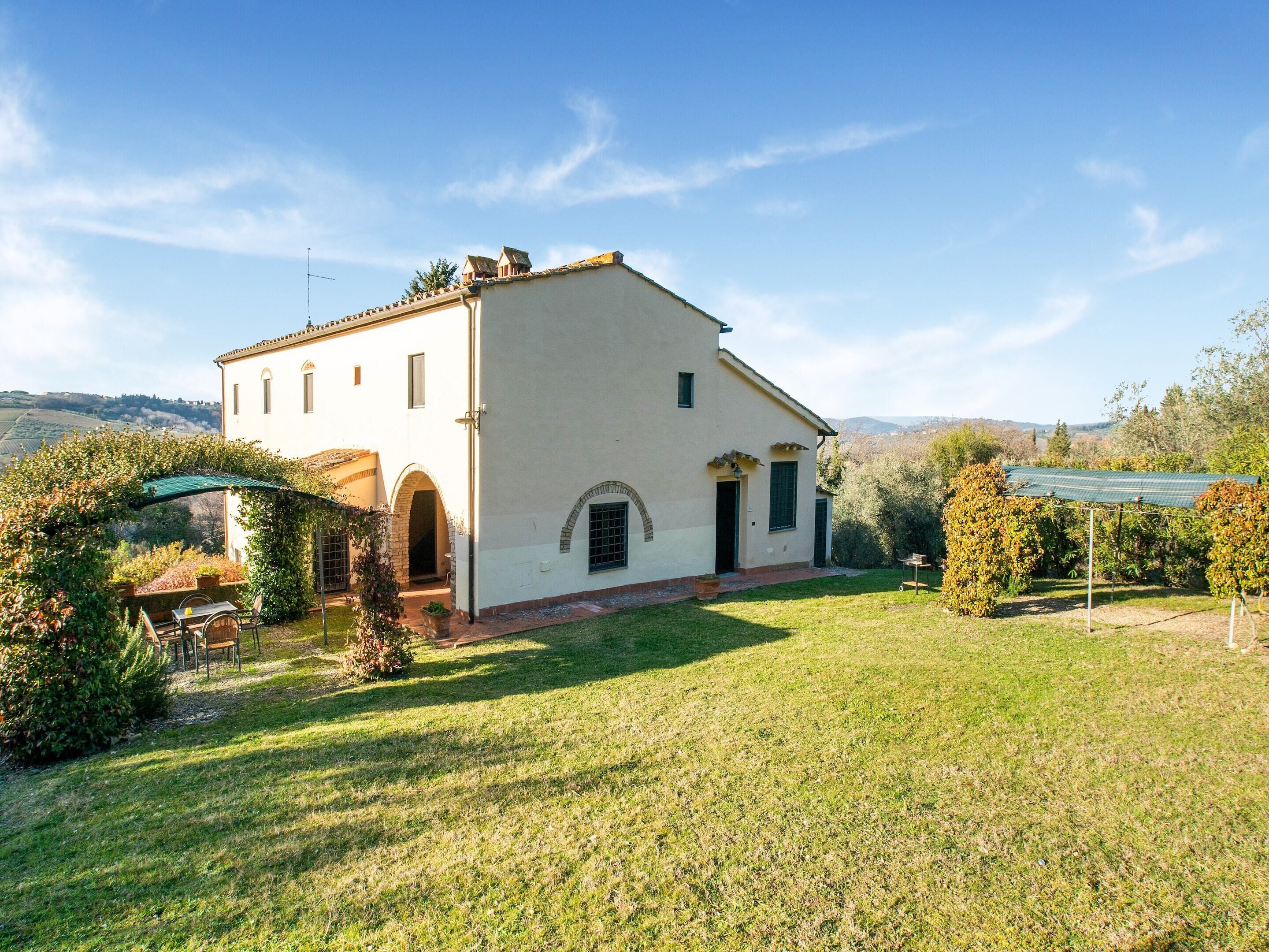 A white building with a garden and a pergola.