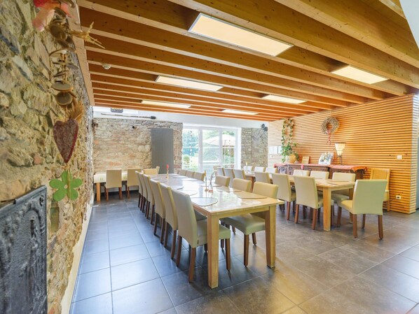 A dining area with wooden beams, stone walls, and tiled flooring.
