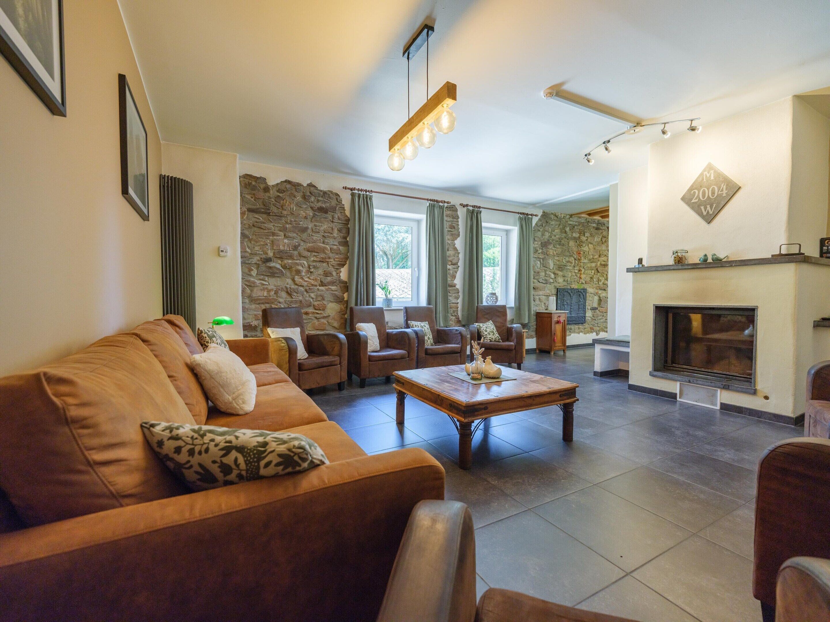A living room with a stone wall, a fireplace, a sofa, and armchairs.