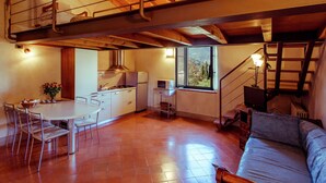 A spacious loft with a kitchen, dining area, and a cozy seating area. - Belvilla by OYO Trilo Della Cascina (Salò)