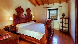 A bedroom with a wooden bed, nightstands, a window with a view, and a wooden cabinet. - Belvilla by OYO Trilo Della Cascina (Salò)
