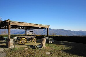 Un pabellón de madera con un banco y un carrito con ruedas amarillas, frente a un paisaje montañoso.
